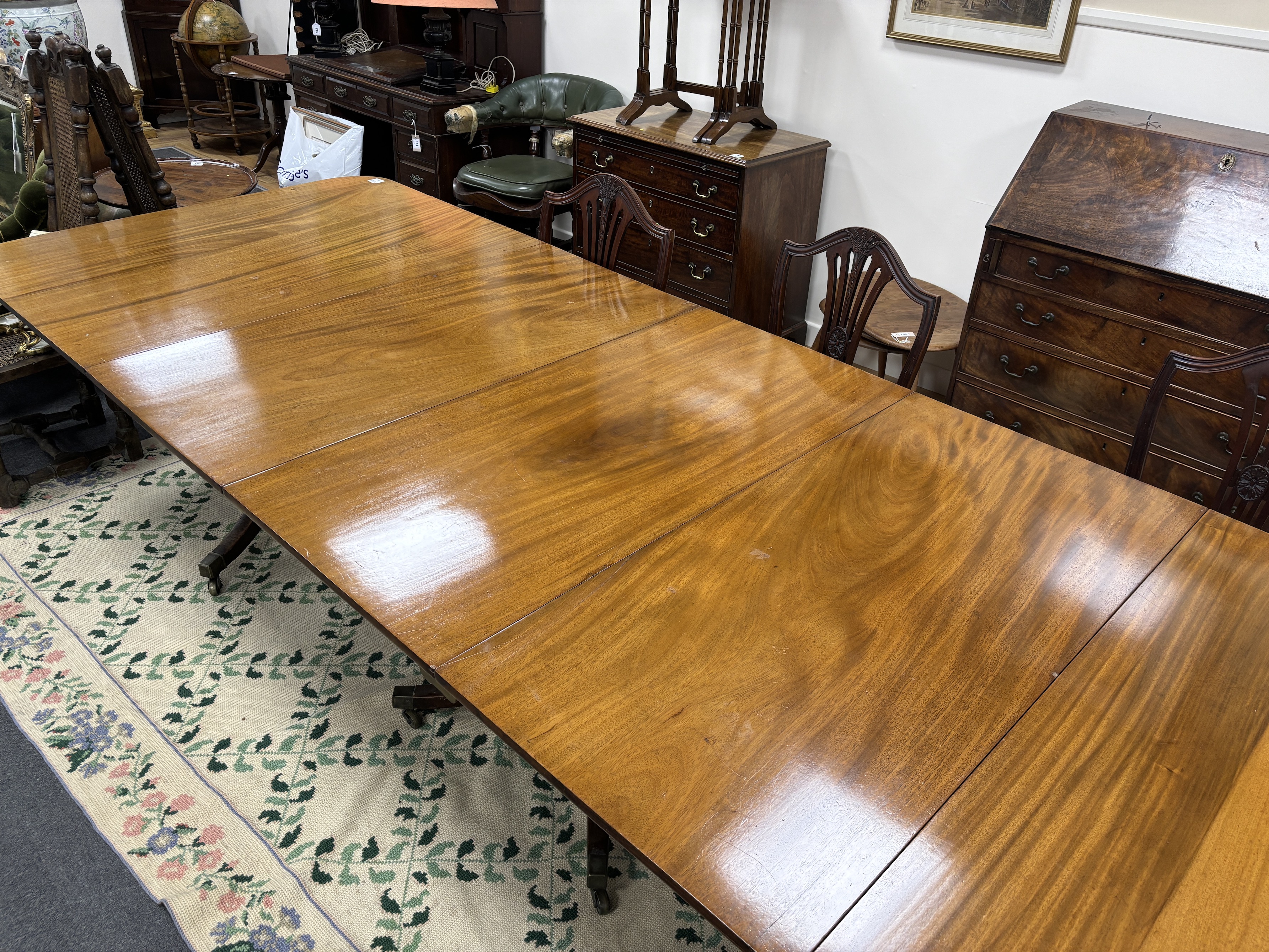 A George III style mahogany triple pillar extending dining table, 346cm extended, two spare leaves, depth 118cm, height 75cm